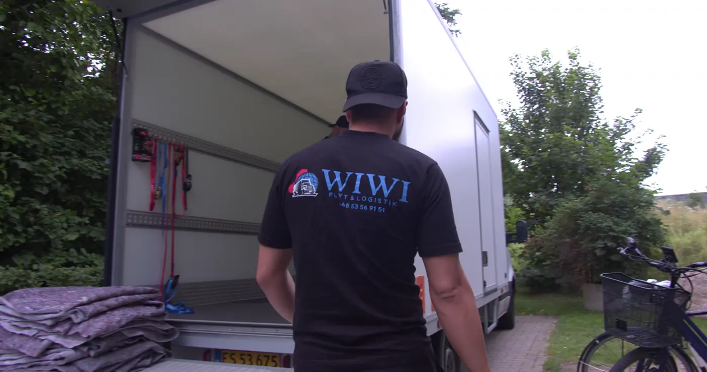 Flyttemand fra Wiwi Flyt ved flyttebilen med flyttetæpper klar på liften